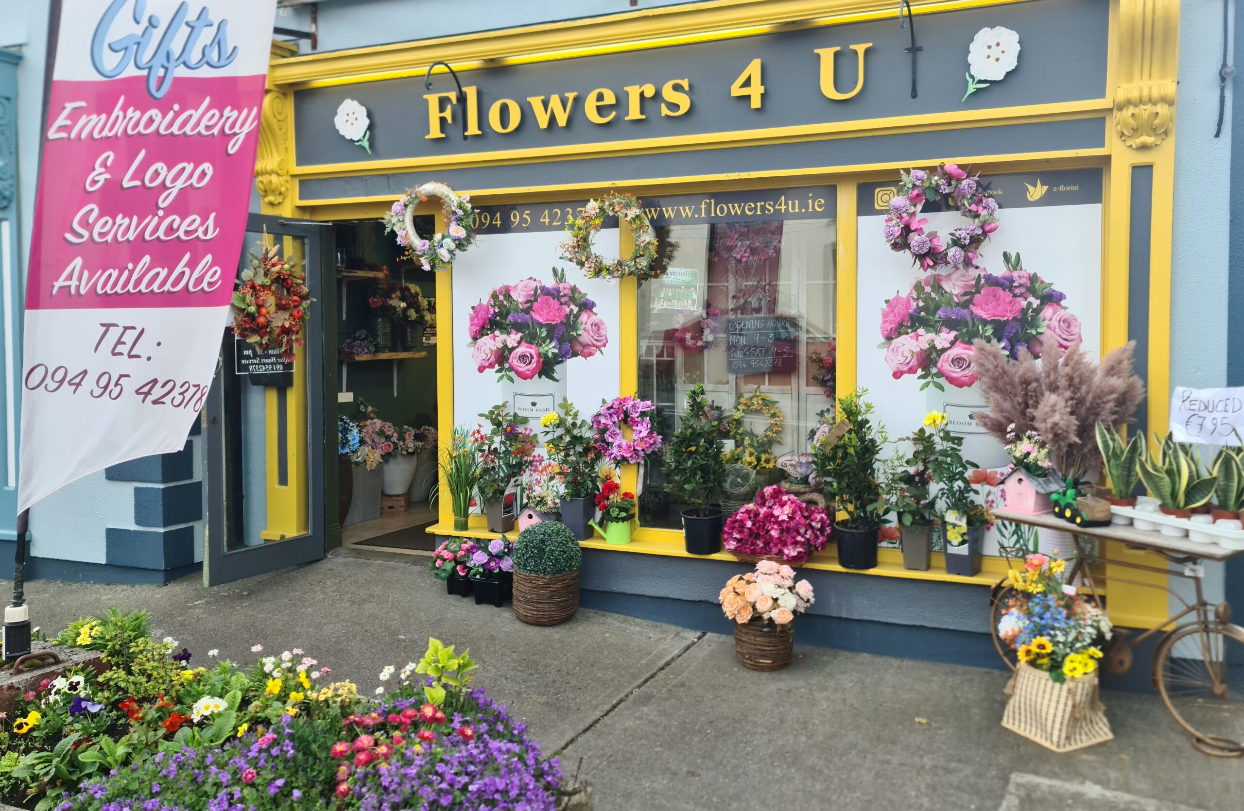 a store front with flowers on the front