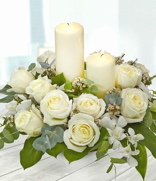 a white roses and candles in a floral arrangement