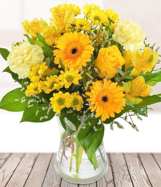 a bouquet of yellow flowers in a glass vase